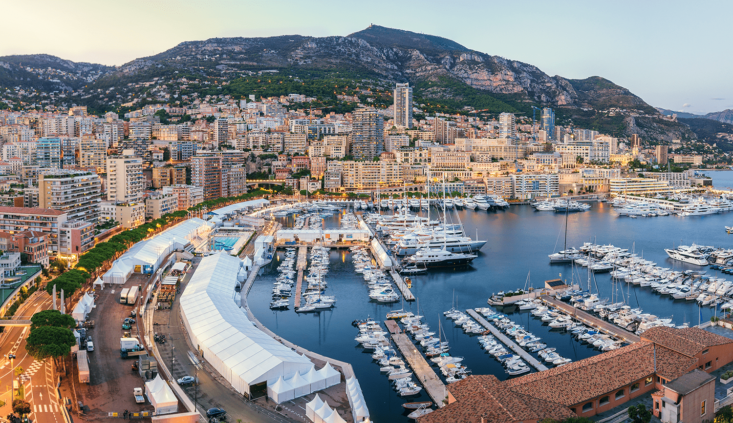 View of the port in Monaco at dusk, with many boats, yachts and superyachts berthed in the harbour