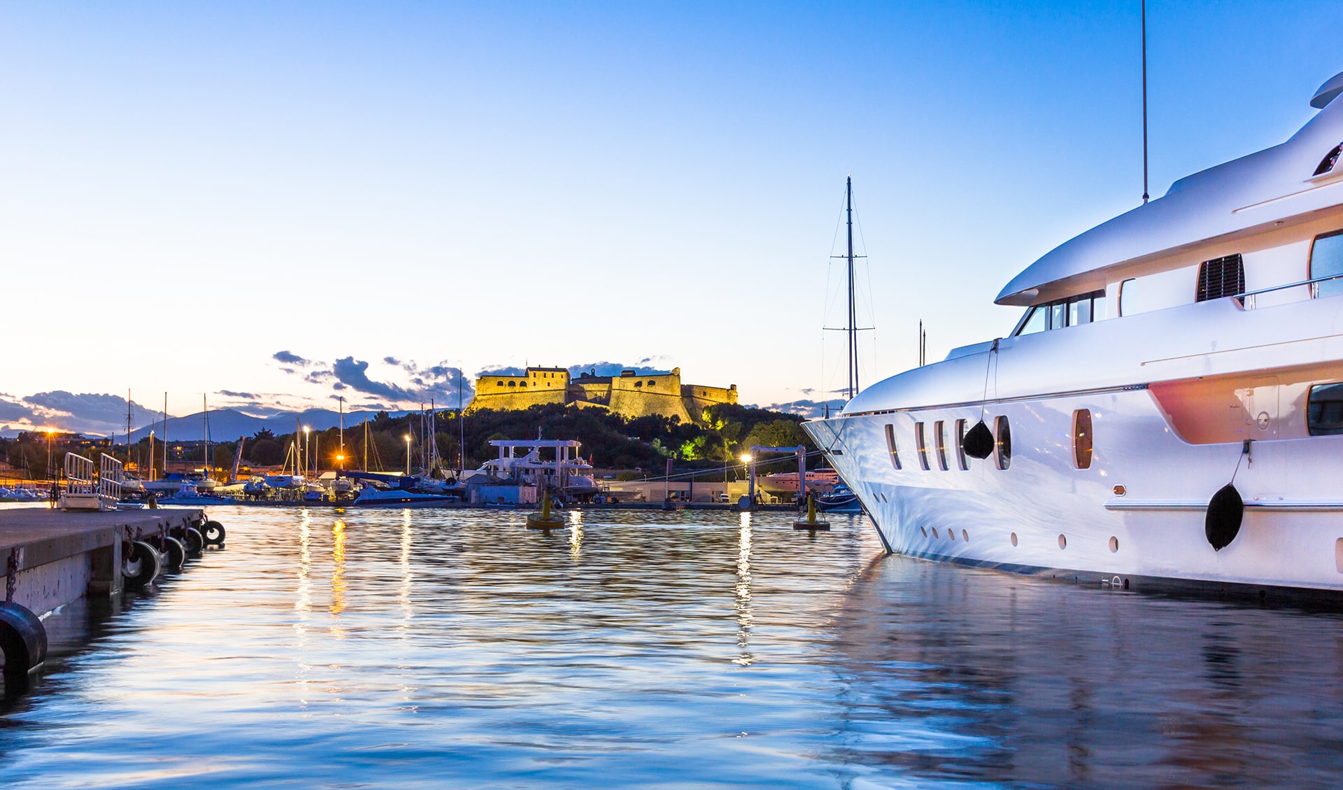 Beautiful view of the Fort Carré from Port Vauban, with a few boats and yachts in the foregrand at dusk.